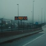 A fog-covered highway with a digital sign warning of heavy fog ahead.